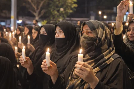 Veiled women holding candles during a prayer vigil at Karbala ground in Delhi