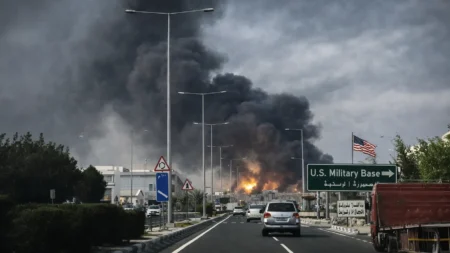Thick black smoke rising in a Gulf city as vehicles drive along a highway following a reported strike targeting US-linked assets