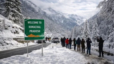 Fresh Snowfall in Himachal Pradesh Lowers Temperatures Across Hill Districts Tourists standing near snow-covered road and mountains after fresh snowfall in Himachal Pradesh