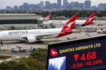 Qantas Shares Drop Over 10% Amid Iran Tensions Qantas aircraft parked at Sydney Kingsford Smith Airport with city skyline in background